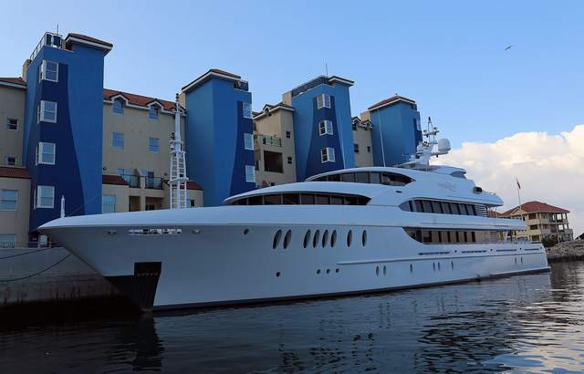 Superyacht moored in front of blue-and-sand apartments at Queensway Quay