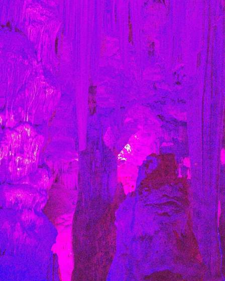 Stalactites lit in purple and pink inside St Michael's Cave